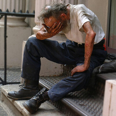 A homeless man with his head in his hands