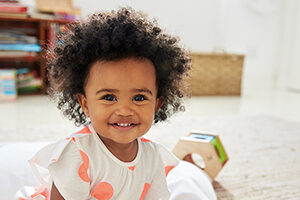 Happy Baby Girl Playing With Toys In Playroom