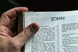 Hand holding open a Bible at the gospel of John