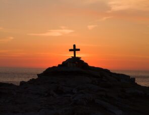 Cross on a mountaintop with a sunset in the background