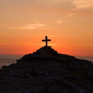 Cross on a mountaintop with a sunset in the background