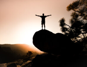 A person standing on top of a mountain with their arms out