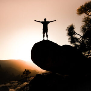 A person standing on top of a mountain with their arms out