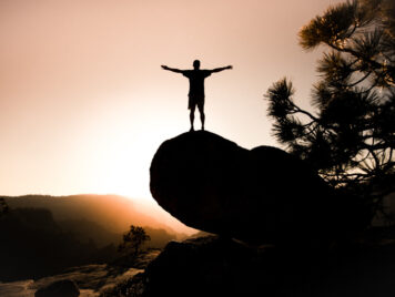 A person standing on top of a mountain with their arms out