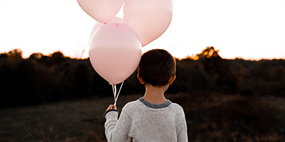 Boy holding three pink balloons