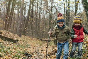 Little boy and girl exploring nature in autumn forest