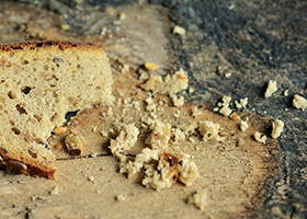 The remains of a slice of bread and crumbs on a wooden surface