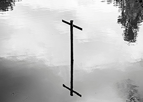 A wooden cross reflected in water