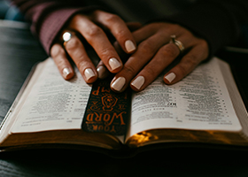 Woman's hands on top of Bible and bookmark open to Psalms